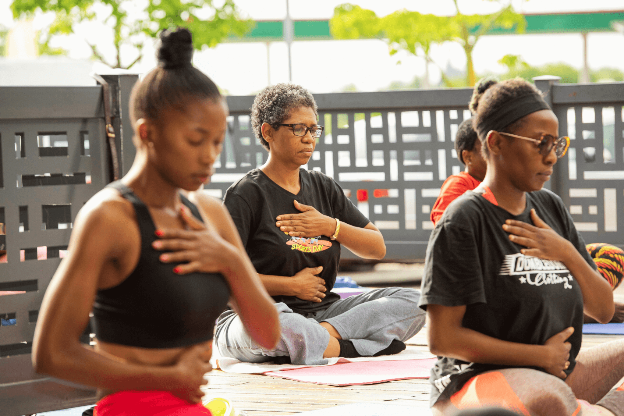 Women seated in a yoga class practicing mindful breathing with hands on chest and abdomen.