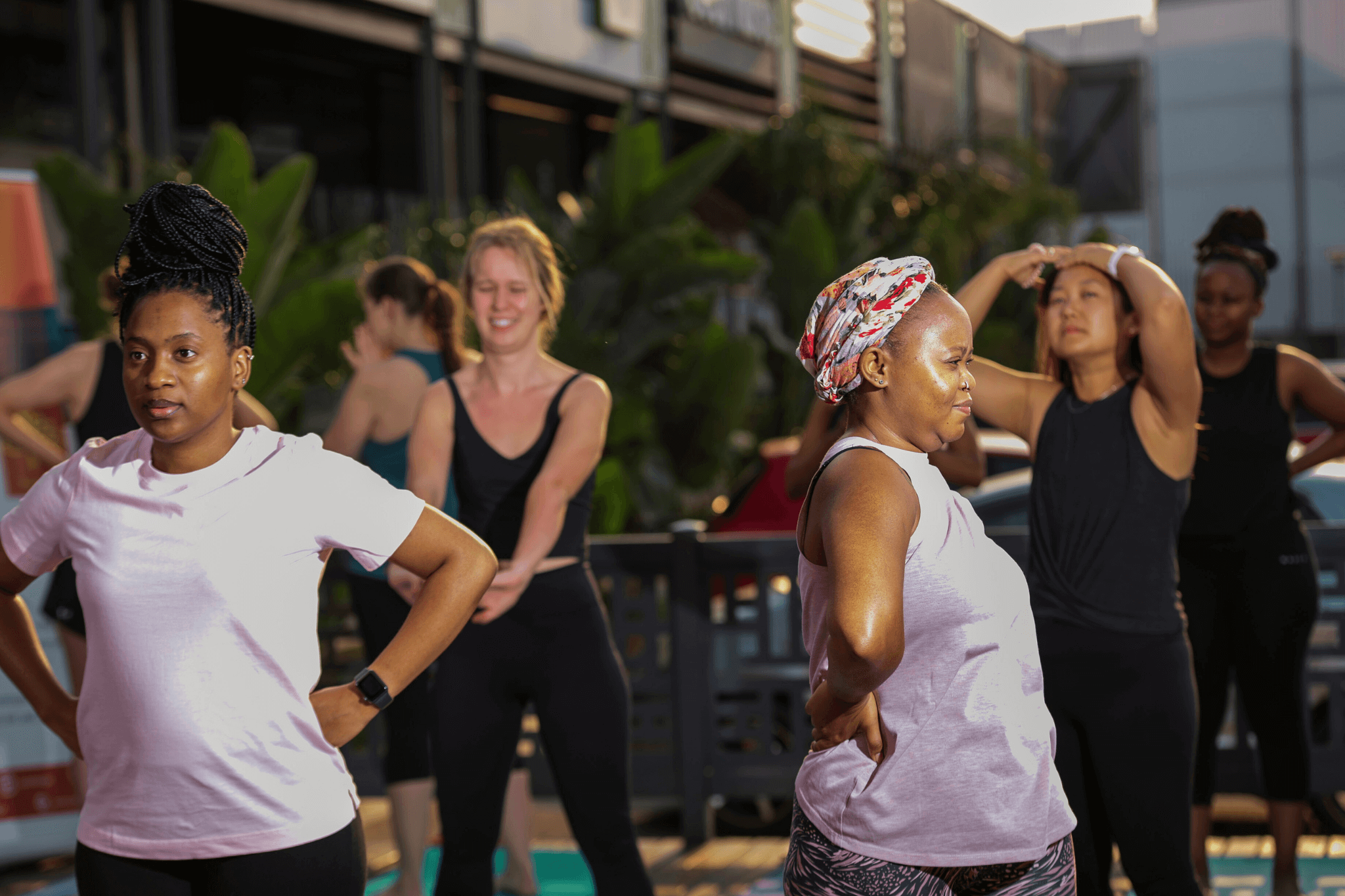 Group of women practicing gentle movement together during an outdoor group wellness session.